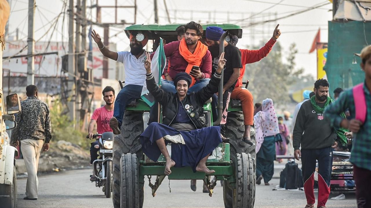 Protesting farmers travel in a tractor at the Singhu Border in New Delhi after Prime Minister Narendra Modi announced the withdrawal of three controversial farm laws. Credit: PTI Photo