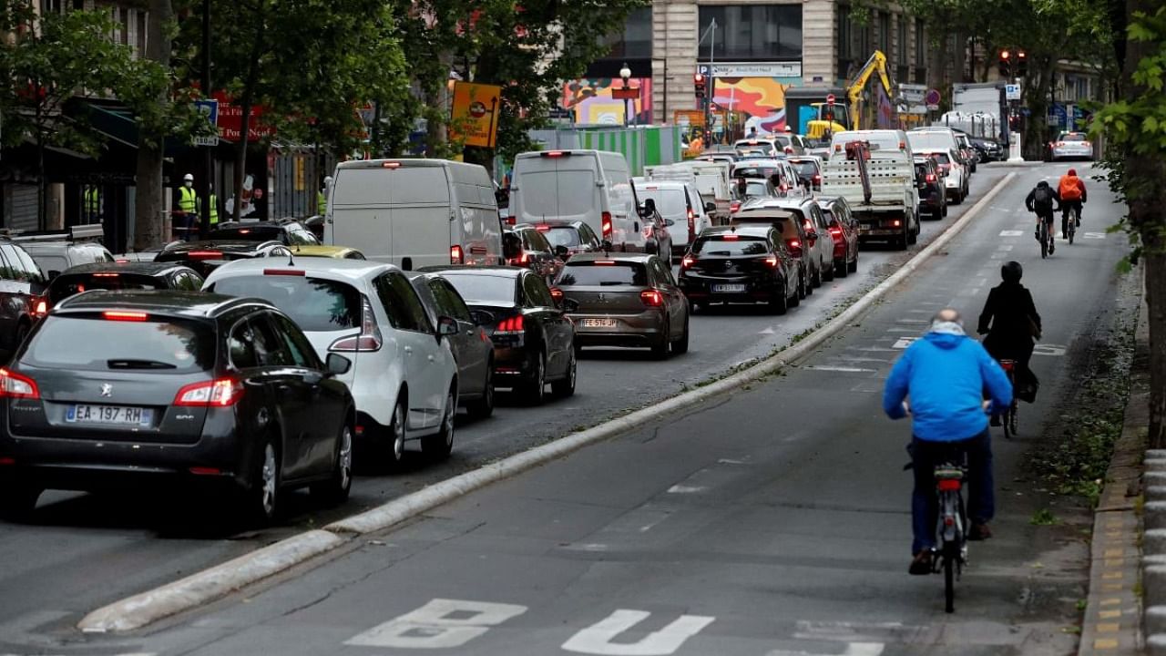 In this file photo taken on May 11, 2020 Commuters ride on their bicycles as cars stop at the traffic light in Paris. Credit: AFP Photo