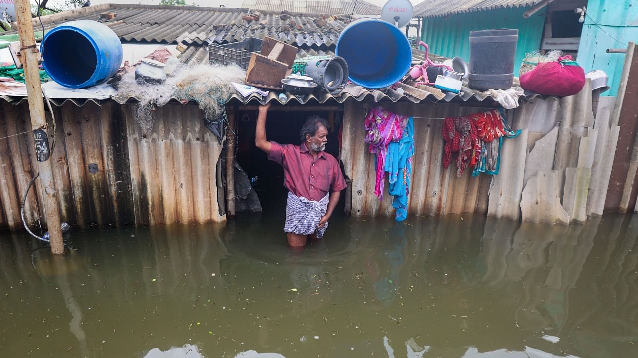 A man stands on the entrance of his waterlogged house after heavy rain at Manali in Chennai. Credit: PTI File Photo