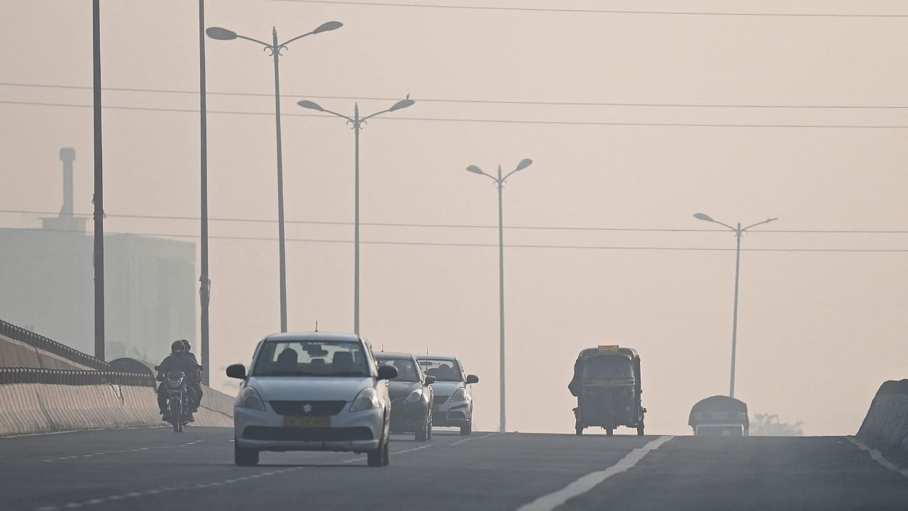 Commuters drive along a road amid heavy smog conditions in New Delhi on November 21, 2021. Credit: AFP Photo