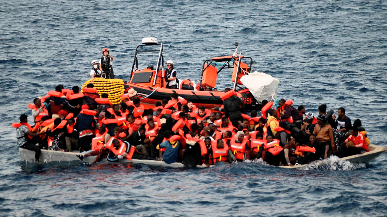 An overcrowded wooden boat packed with 99 migrants is approached by a tender of the humanitarian organization off the Libya coast. Credit: AP Photo