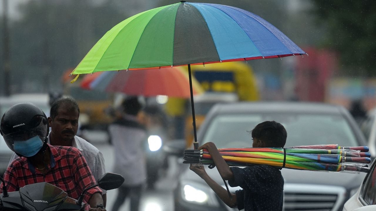 A boy sells umbrellas to commuters along a road as it rains in Chennai. Credit: AFP Photo