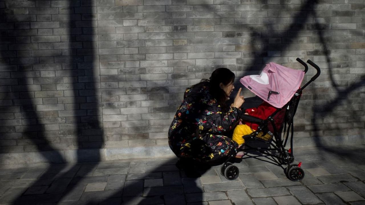 A woman talks to her baby in a stroller in Beijing. Credit: AFP Photo