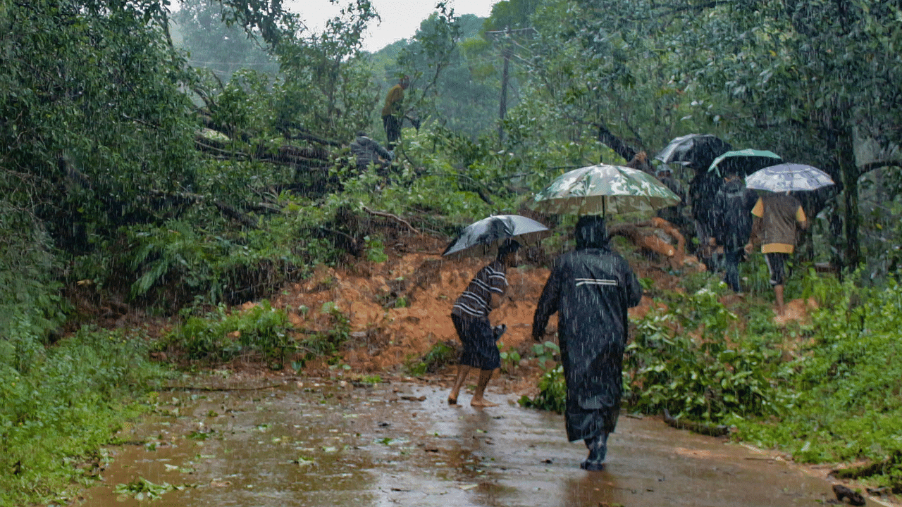 People walk past debris, following landslides on the foothills of the Brahmagiri Hills, during rainfall, in Kodagu. Credit: PTI Photo