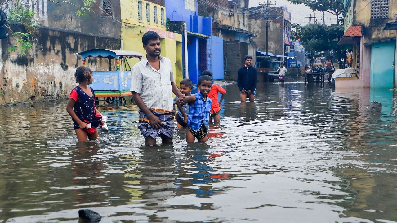 Residents wade through a waterlogged area following heavy rains, in Vellore. Credit: PTI File Photo