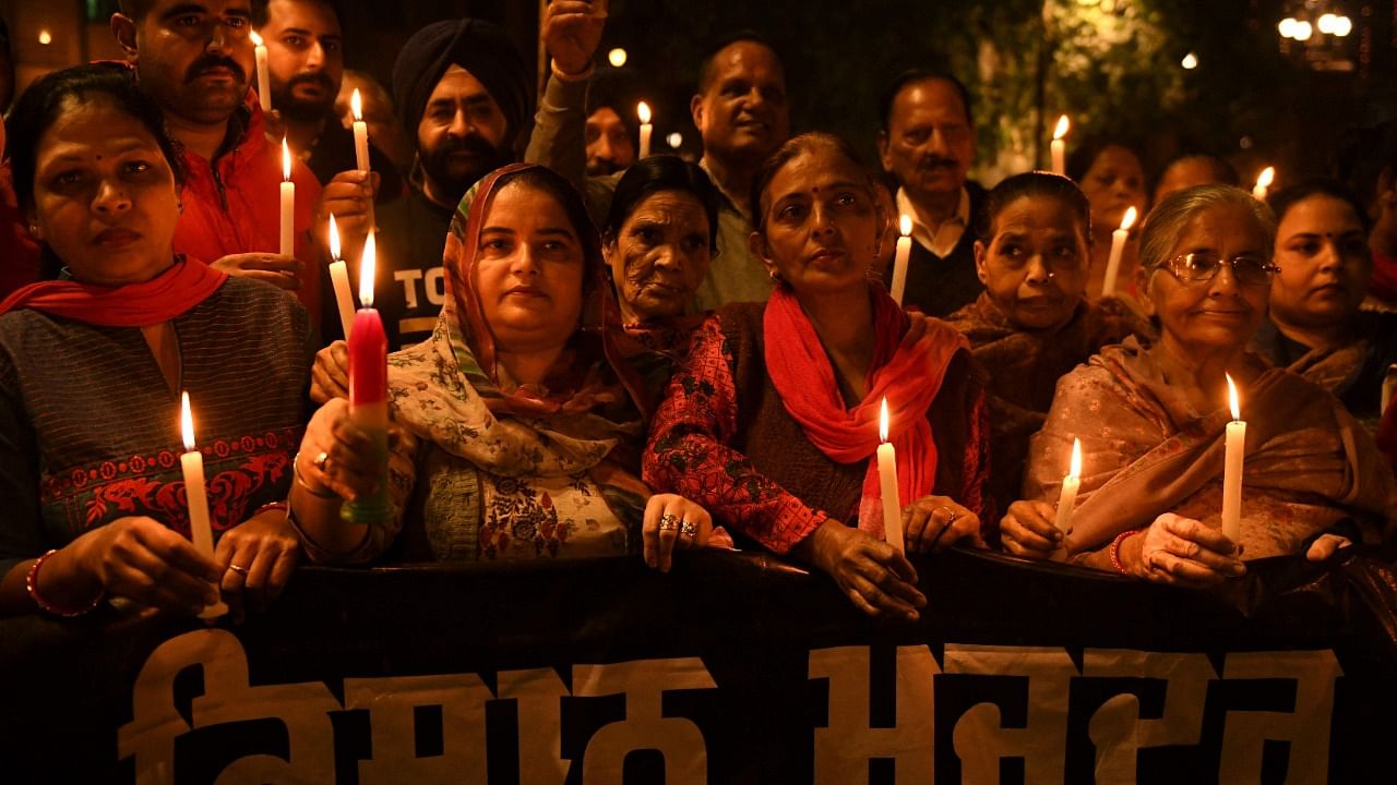 Congress party workers hold candles during a candle march to pay tribute to farmers who lost their lives during protests. Credit: AFP Photo