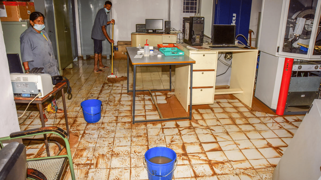 Workers mop up the sewage-mixed rainwater that gushed into a lab at the Jawaharlal Nehru Centre for Advanced Scientific Research, Jakkur, on Tuesday. Credit: DH Photo