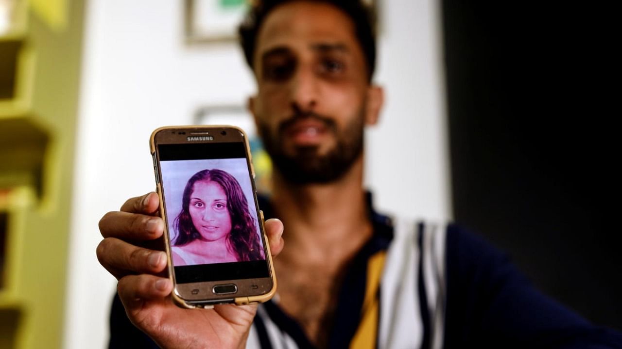 Liron Ozeri, holds up his phone showing the Listen to Our Voice campaign video which marks the International Day for the Elimination of Violence Against Women, and shows the face of his sister Sagit Ozeri who was strangled to death by her partner after calling for help in Tel Aviv. Credit: Reuters photo