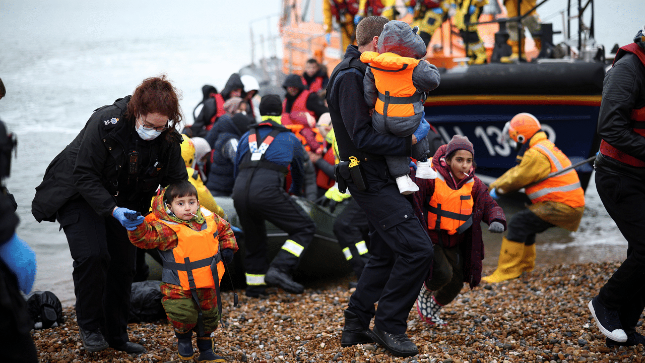 Migrants are brought ashore by RNLI Lifeboat staff, police officers and Border Force staff, after having crossed the channel, in Dungeness. Credit: Reuters Photo