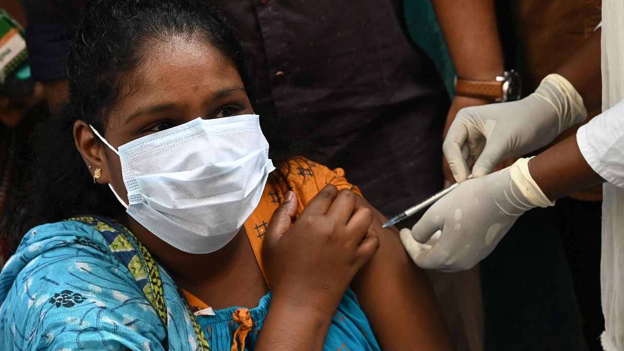 A woman reacts as a health worker inoculates her with a dose of the Covid-19. Credit: AFP Photo
