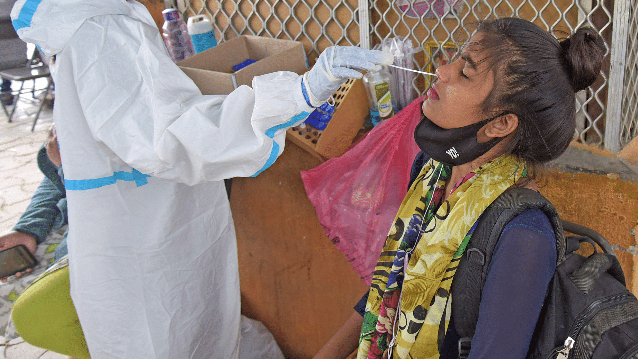 A health care worker collects swab sample from people for coronavirus. Credit: DH Photo
