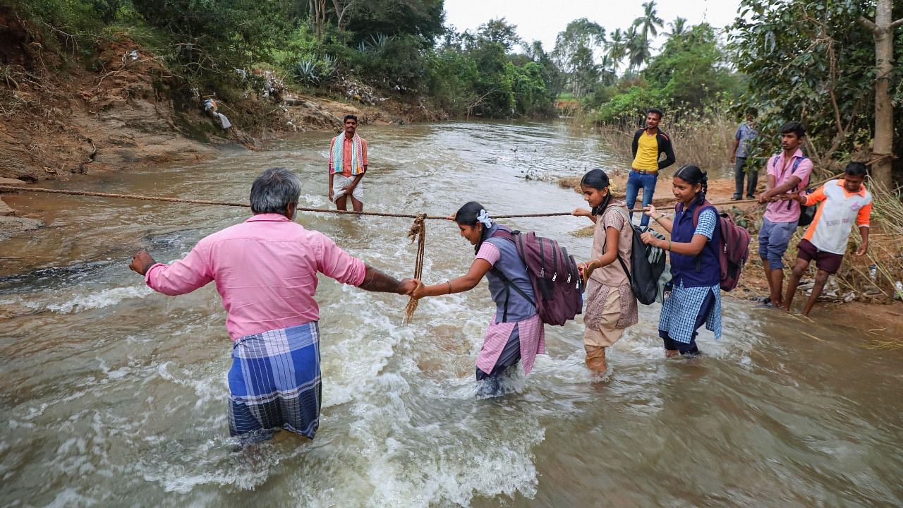 Students cross an overflowing river using a rope after heavy rain at Veppanapalli, in Krishnagiri district, Thursday, November 25, 2021. Credit: PTI Photo