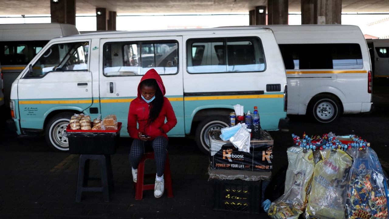 A street hawker looks at her mobile phone as she sits next to her wares after the announcement of a British ban on flights from South Africa because of the detection of a new Covid-19 variant, in Soweto, South Africa. Credit: Reuters photo
