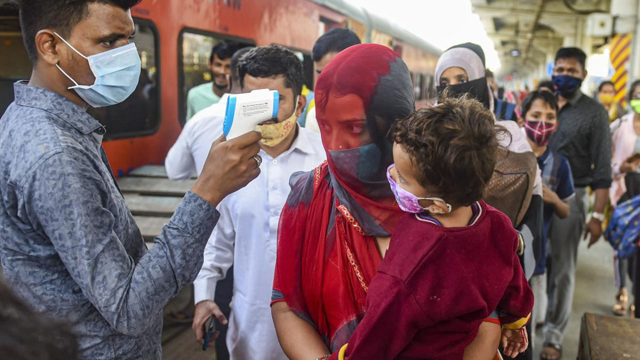 A BMC health worker conducts thermal screening of outstation passengers for Covid-19 testing at Dadar Railway Station in Mumbai. Credit: PTI Photo