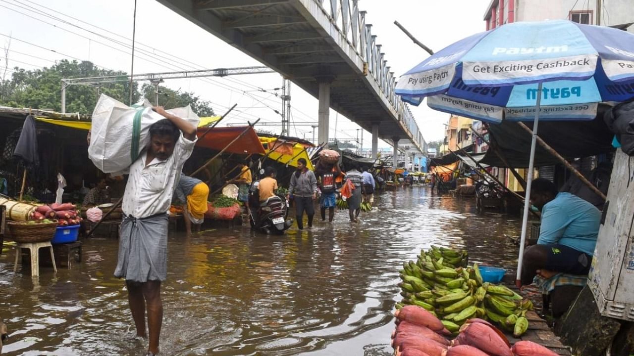 Chennai:People wade past floodwaters on the outskirts of Chennai following heavy rain. Credit: IANS Photo