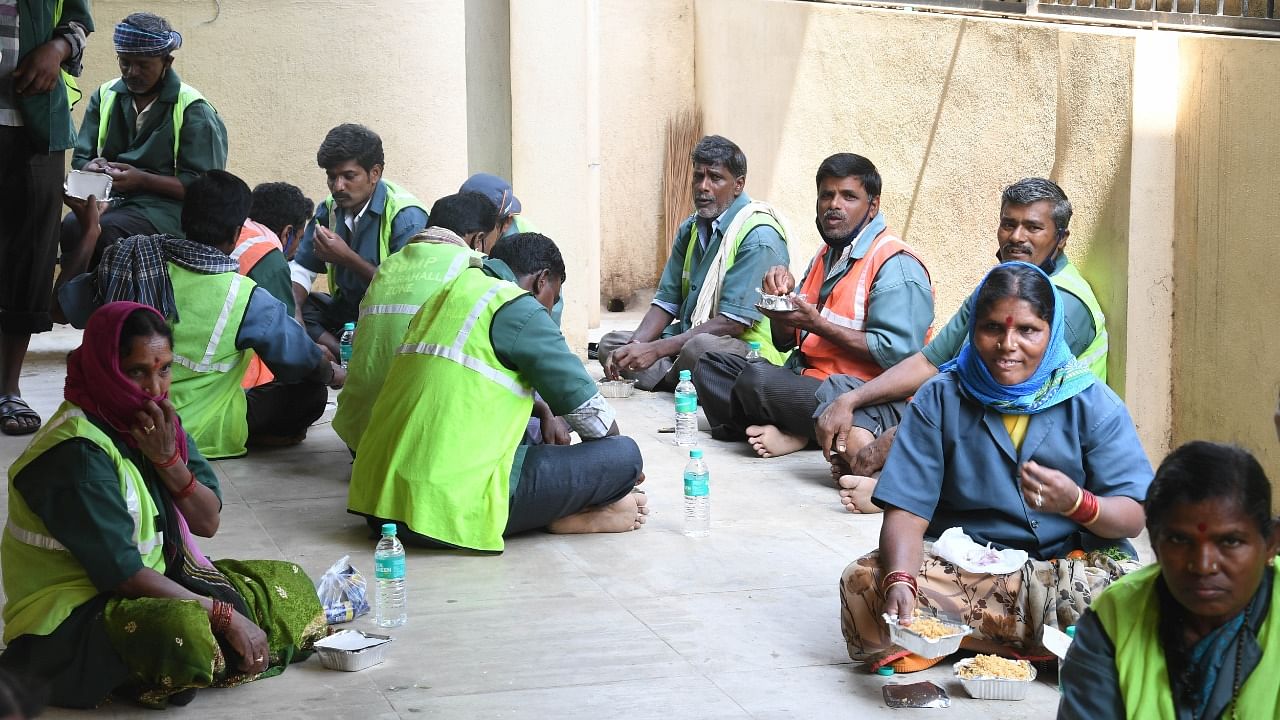 BBMP’s Pourakarmikas get a break for lunch after cleaning the streets. Credit: DH Photo