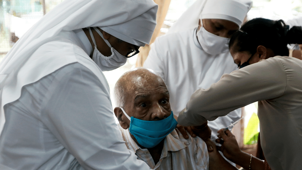 Nuns hold an elderly man as he receives a dose of COVAXIN coronavirus disease (Covid-19) vaccine. Credit: Reuters Photo