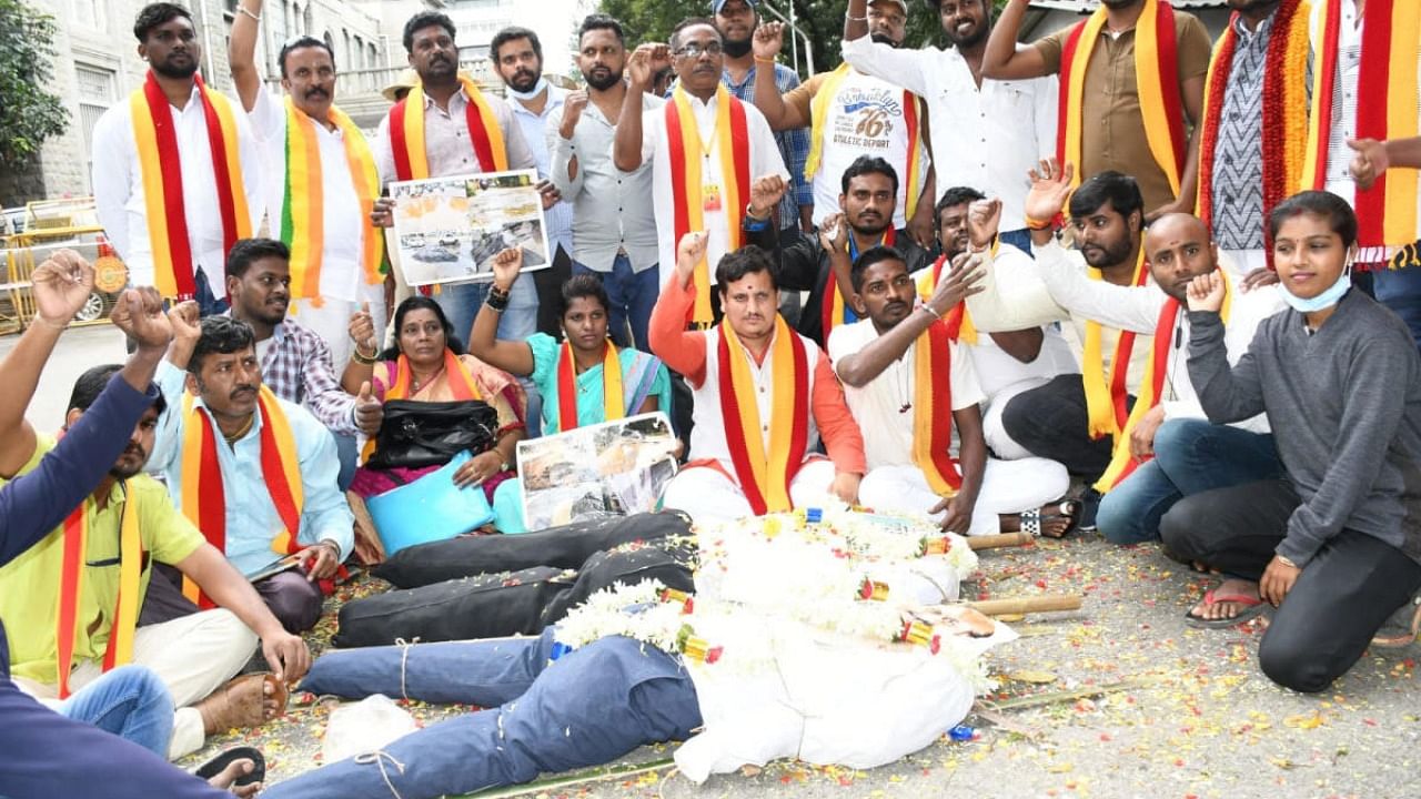 Activists sat in front of mock corpses as they protested against pothole-filled roads that have become death traps for motorists. Credit: Special arrangement