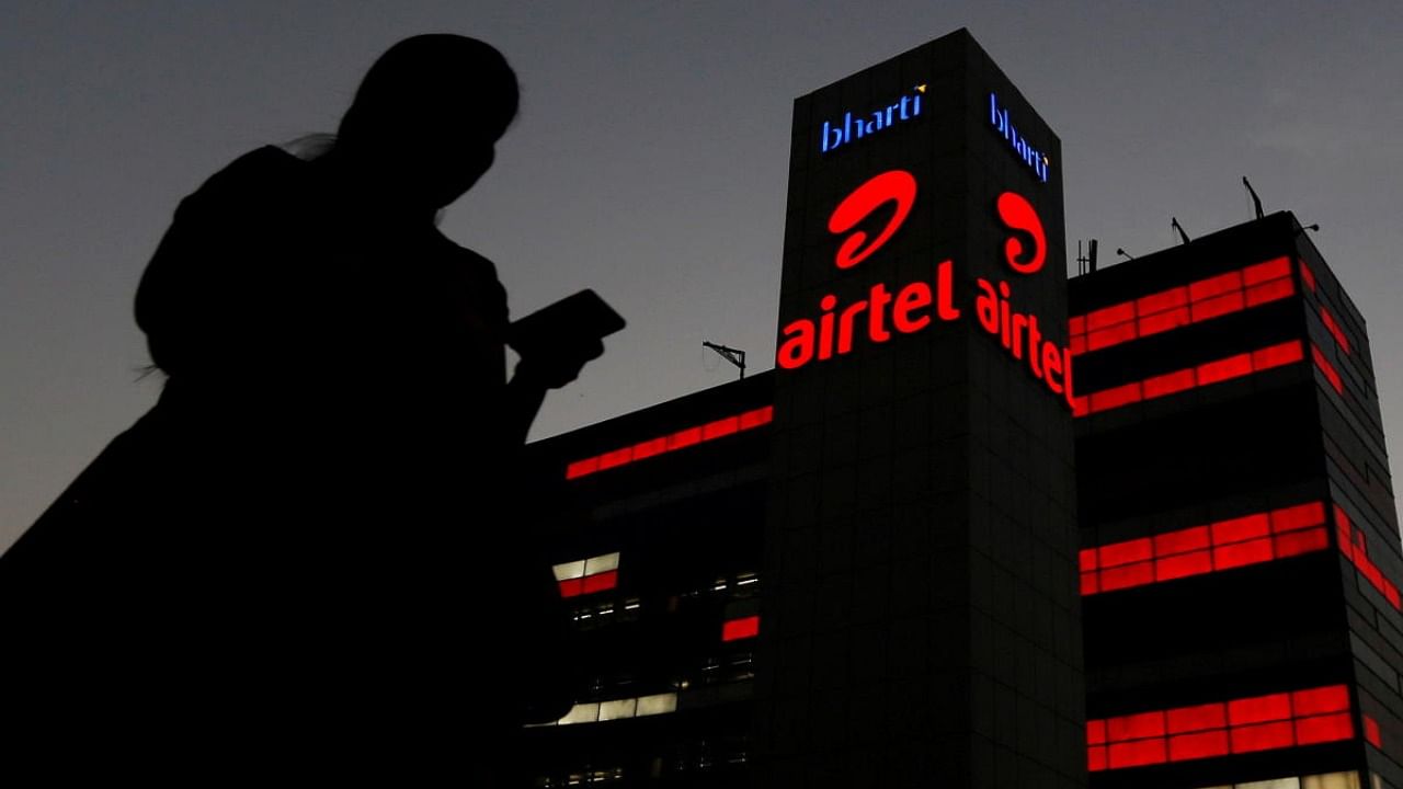A girl checks her mobile phone as she walks past the Bharti Airtel office building in Gurugram. Credit: Reuters Photo