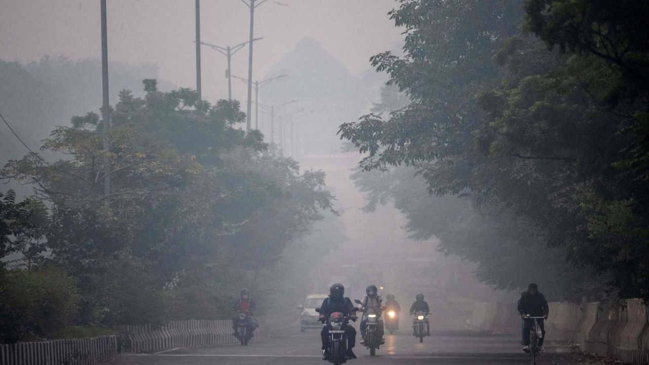 People commute along a street amid smoggy conditions in New Delhi. Credit: AFP Photo