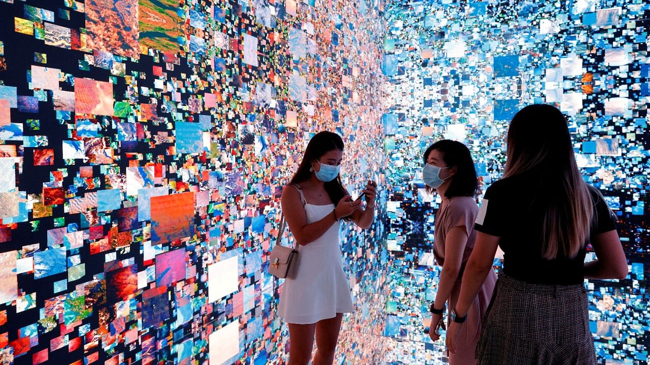 Visitors are pictured in front of an immersive art installation titled "Machine Hallucinations — Space: Metaverse" by media artist Refik Anadol, which will be converted into NFT and auctioned online at Sotheby's, at the Digital Art Fair, in Hong Kong, China September 30, 2021. Credit: Reuters File Photo