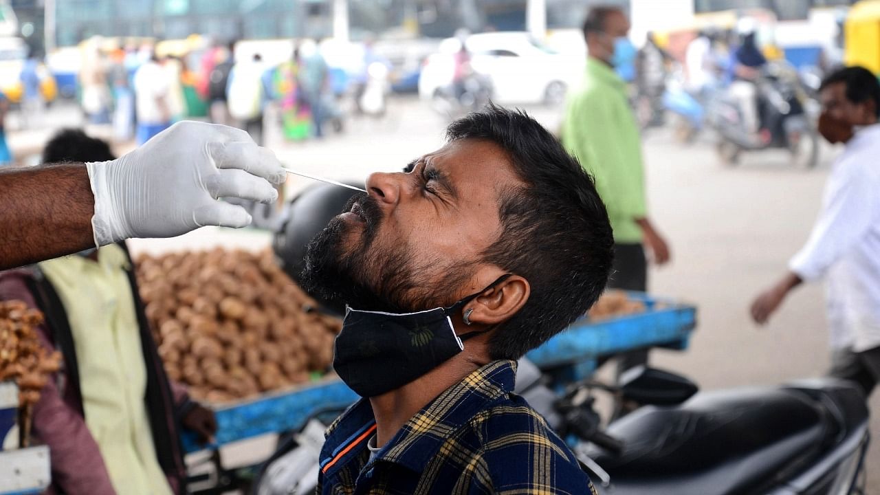A health worker collects a nasal sample from a man for Covid-19 testing, at KR market in Bengaluru on Thursday, December 02, 2021. Credit: IANS