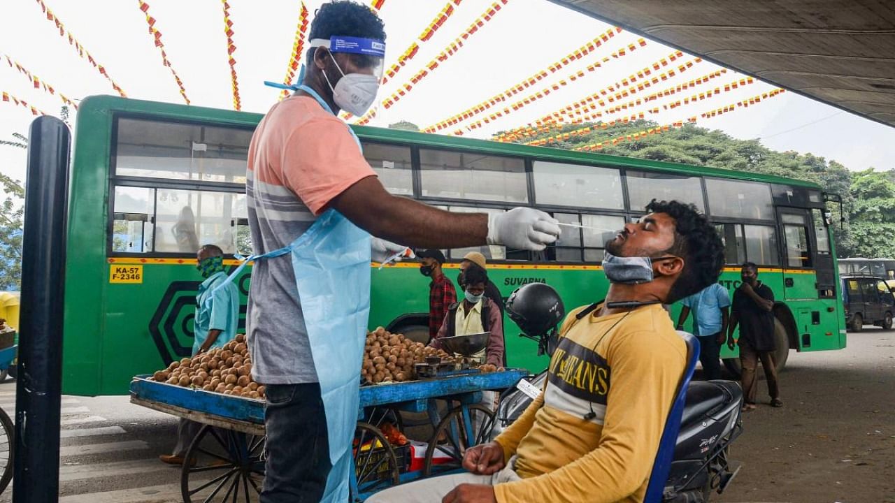 A medic collects swab sample of a commuter for Covid-19 test, in Bengaluru. Credit: PTI Photo