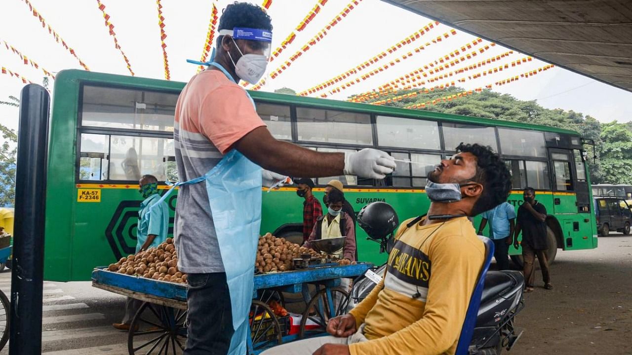 A medic collects swab sample of a commuter for Covid-19 test, in Bengaluru. Credit: PTI Photo