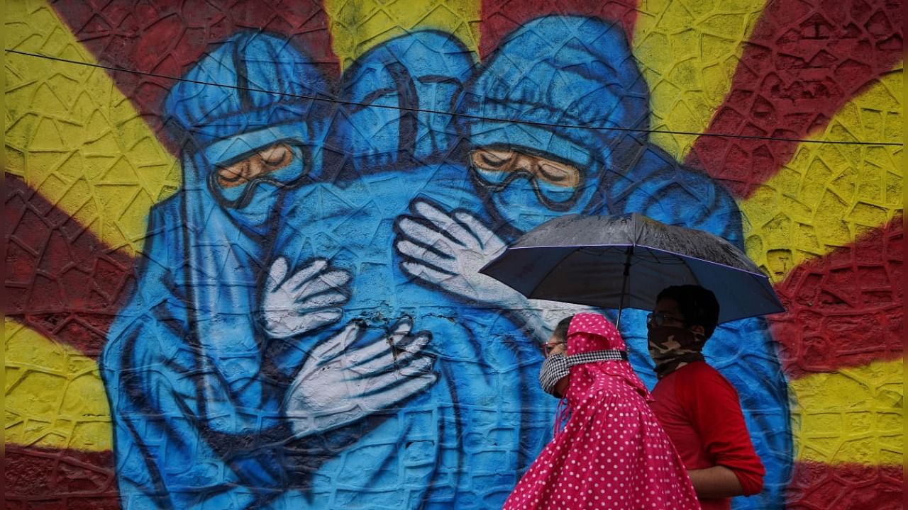 A woman and her son walk past a graffiti on a street, amidst the coronavirus disease (COVID-19) pandemic, in Mumbai, India, December 1, 2021. Credit: Reuters Photo