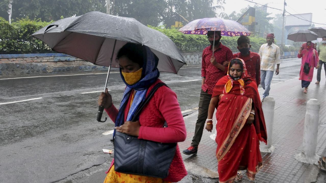 People use umbrellas to protect themselves from rain as they walk on a road, amid Cyclone Jawad threat, in Kolkata. Credit: PTI Photo
