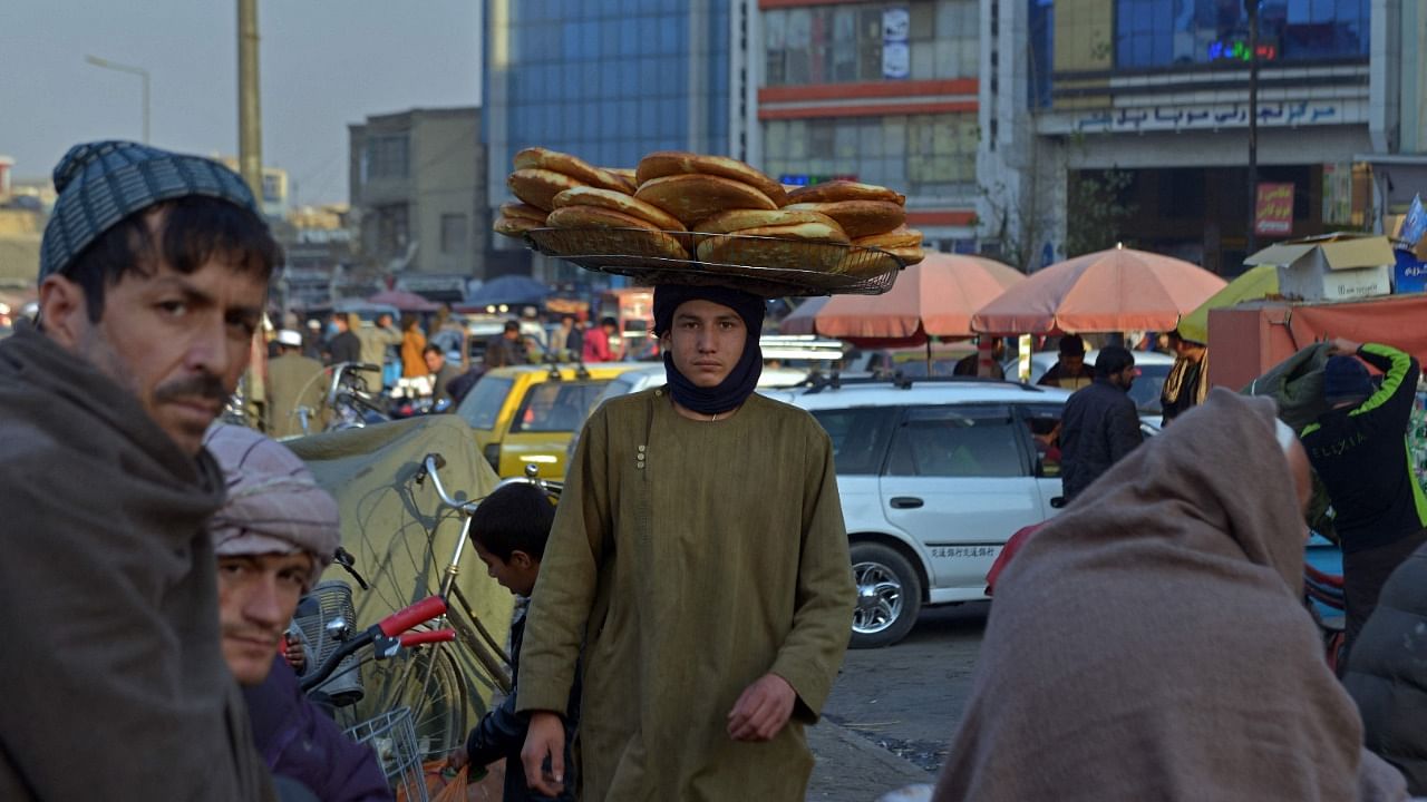 A vendor walks while selling bread at a street market in the Pul-e Khishti area of Kabul on December 2, 2021. Credit: AFP File Photo