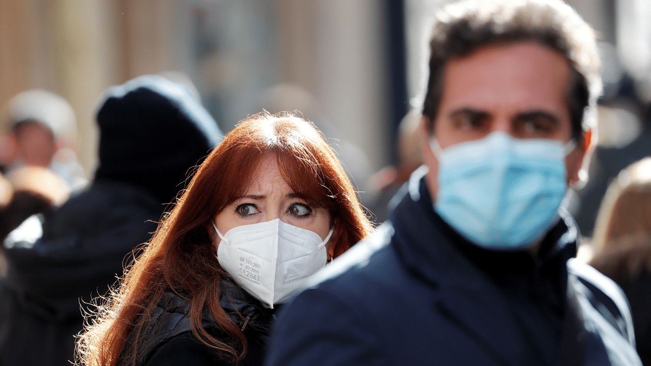 People wear protective masks as they walk down Via del Corso, Rome's main shopping street. Credit: Reuters Photo