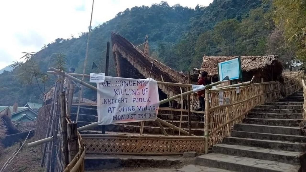 A man walks behind a placard posted at the venue of the Hornbill festival which was shut after Indian security forces killed 13 civilians in the northeastern state of Nagaland firing on a truck and later shooting at a crowd that gathered to protest the attack, at Kisama village in Kohima on December 5, 2021. Credit: AFP Photo