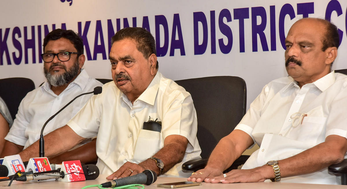 Former minister B Ramanath Rai speaks to reporters at district Congress Committee office in Mangaluru on Monday. District Congress president Harish Kumar and leader Shahul Hamid look on. Credit: DH Photo