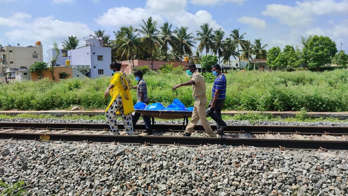 Ashy V Swamy (L) seen carrying a body away from a railway track. Credit: Special Arrangement