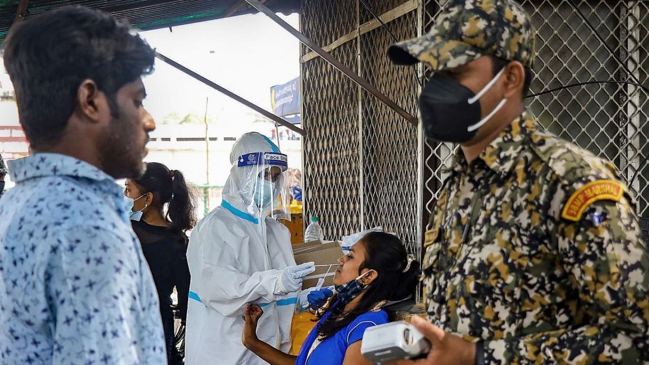 A health worker collects swab sample of commuter for Covid-19 test, amid fear of spreading of 'Omicron' variant, at KSRTC bus stand, in Bengaluru. Credit: PTI Photo