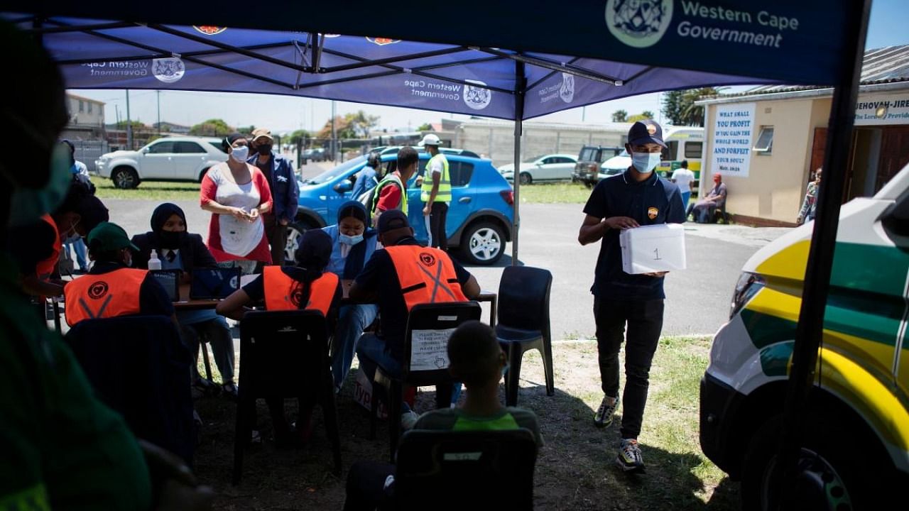 People register before getting vaccinated outside an ambulance which has been converted to facilitate vaccinations at a Covid-19 vaccination event in Manenberg. Credit: AFP Photo