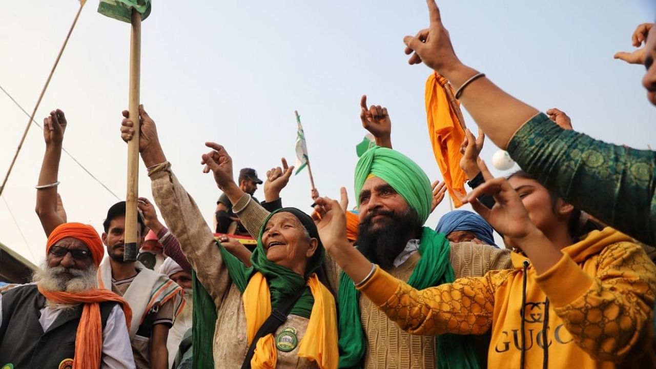 Farmers celebrate following the announcement of suspension of their year-long protest against farm laws & other related issues, at Singhu border in New Delhi on Thursday. Credit: IANS Photo