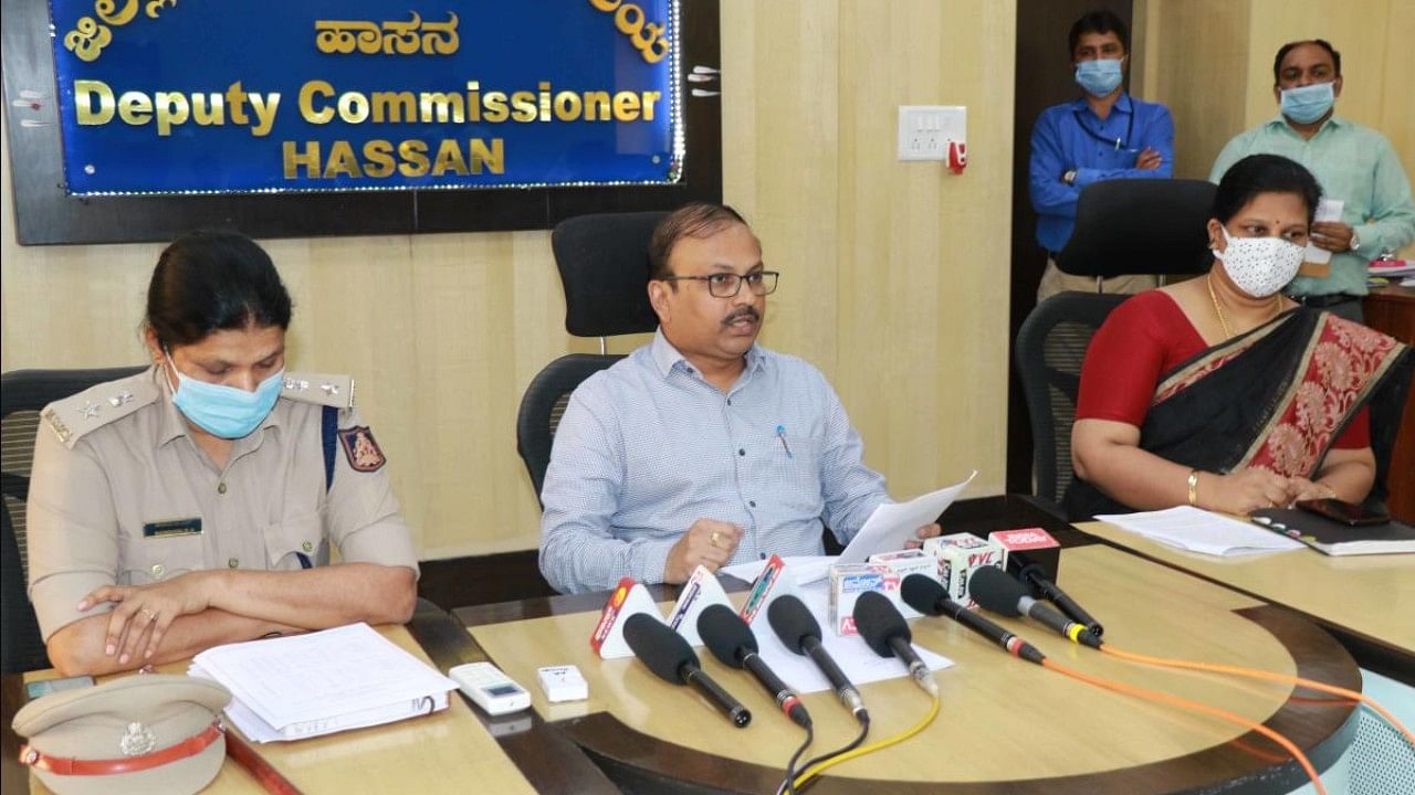 Deputy Commissioner R Girish addresses the press at the DC Office in Hassan on Wednesday. Additional Superintendent of Police B N Nandini and Additional Deputy Commissioner Kavitha Rajaram are seen. Credit: DH Photo