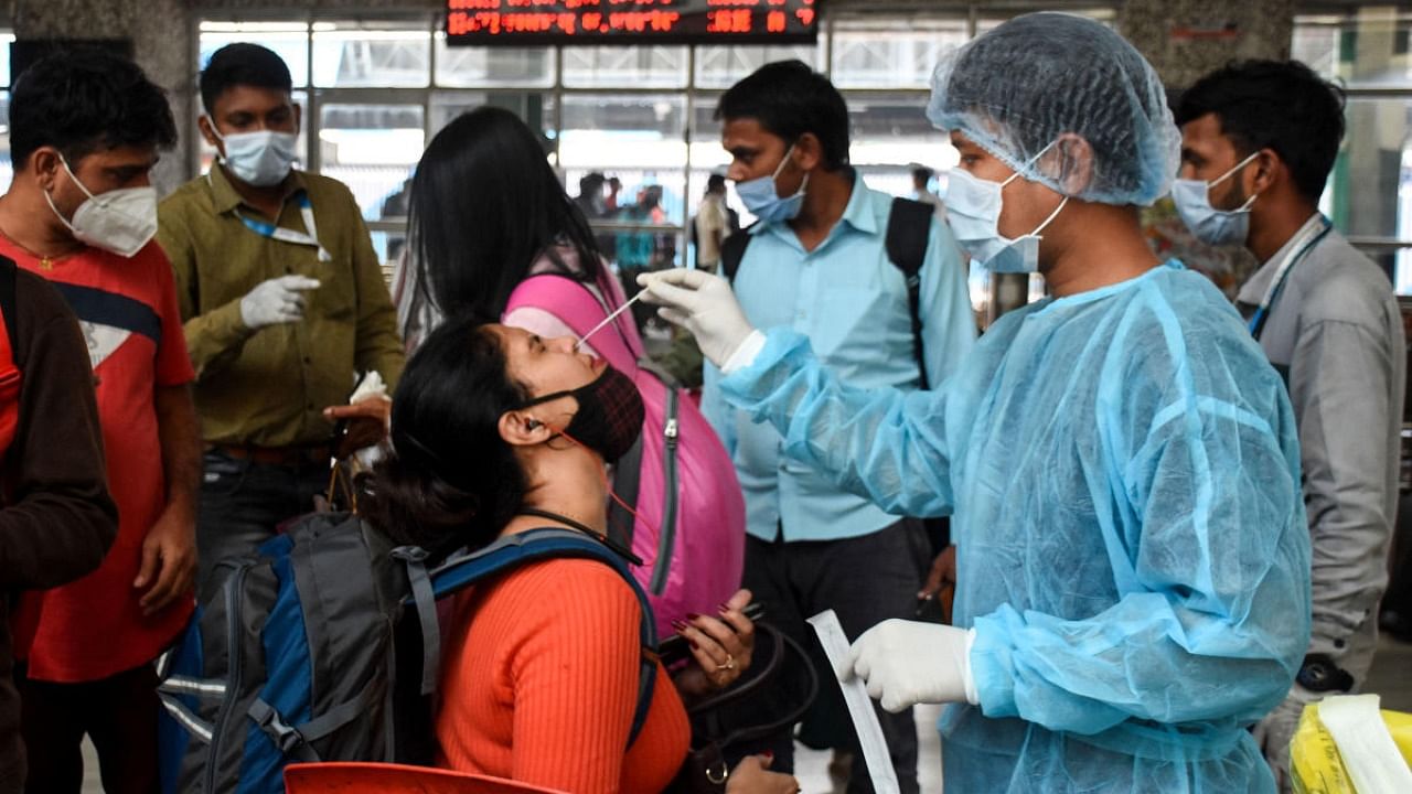 A healthcare worker collects a swab sample of a passenger for Covid-19 test, at Bandra Terminal, in Mumbai. Credit: PTI Photo