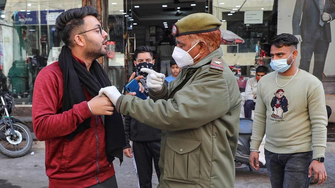 A policeman forces a pedestrian to take the Covid-19 test as he was not wearing a face mask, in Jammu, Friday. Credit: PTI Photo