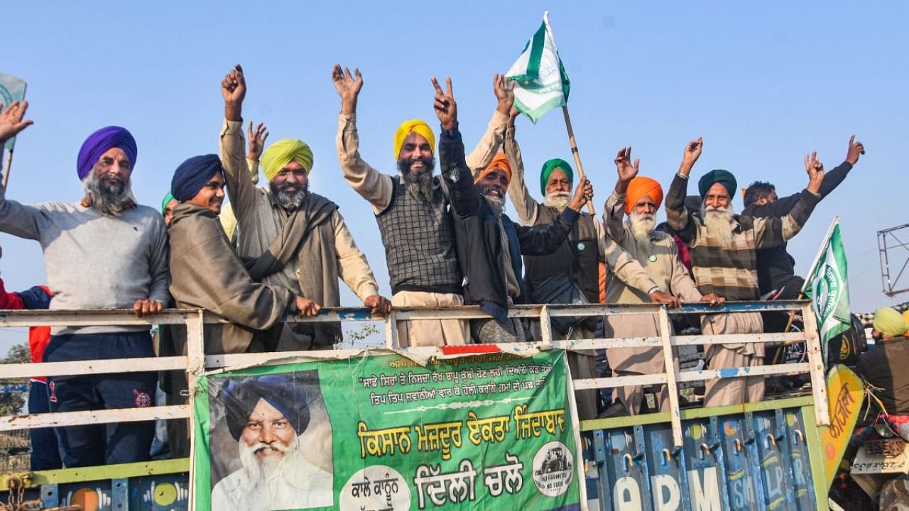 Farmers flash the victory sign as they leave from the Singhu border after their year-long agitation against contentious farm reform laws, in New Delhi. Credit: PTI Photo