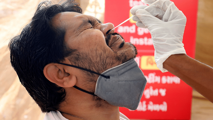 A man reacts as a healthcare worker collects a swab sample from him to test for the coronavirus disease. Credit: Reuters Photo