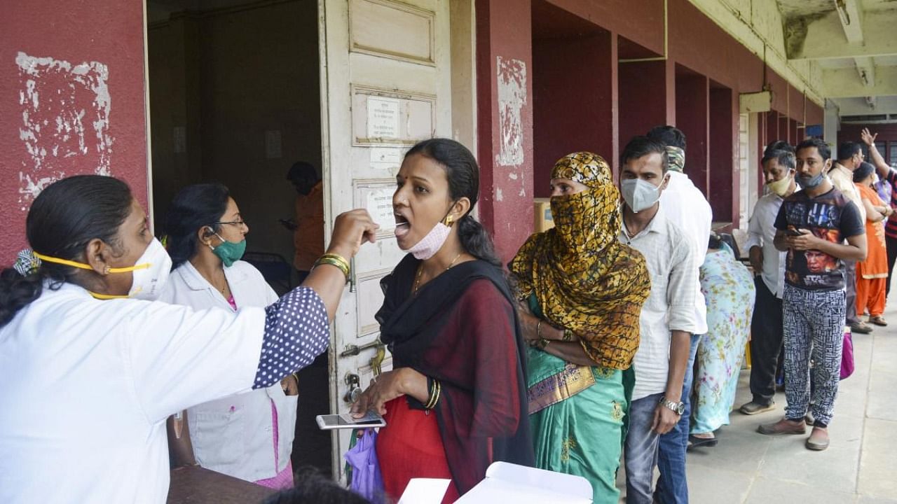 A health worker collects swab samples of a woman for Covid-19 test, in Karad, Maharashtra. Credit: PTI Photo