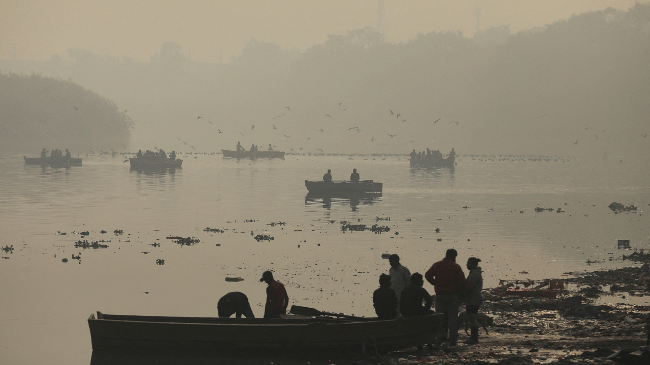 People ride on boats on the Yamuna river on a smoggy morning in New Delhi. Credit: Reuters Photo