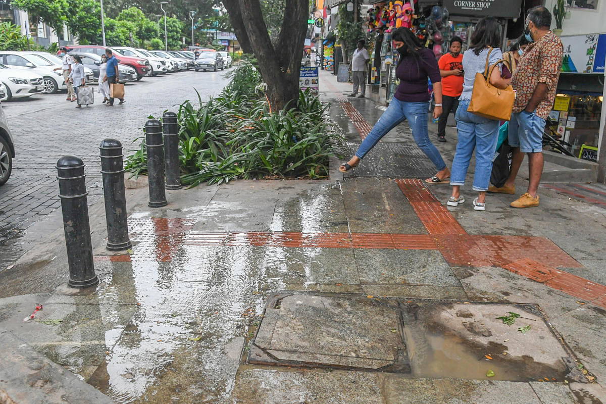 People waded through dirty water on Church Street as sewage water overflowed from a manhole on Saturday. Passersby said the stench was unbearable. Credit: DH PHOTO/S K Dinesh
