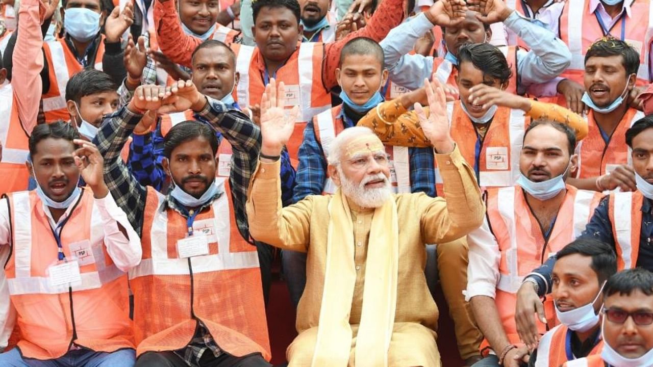  Prime Minister Narendra Modi with the workers involved in construction work of Kashi Vishwanath Dham Corridor in Varanasi on Monday, December 13, 2021. Credit: IANS Photo