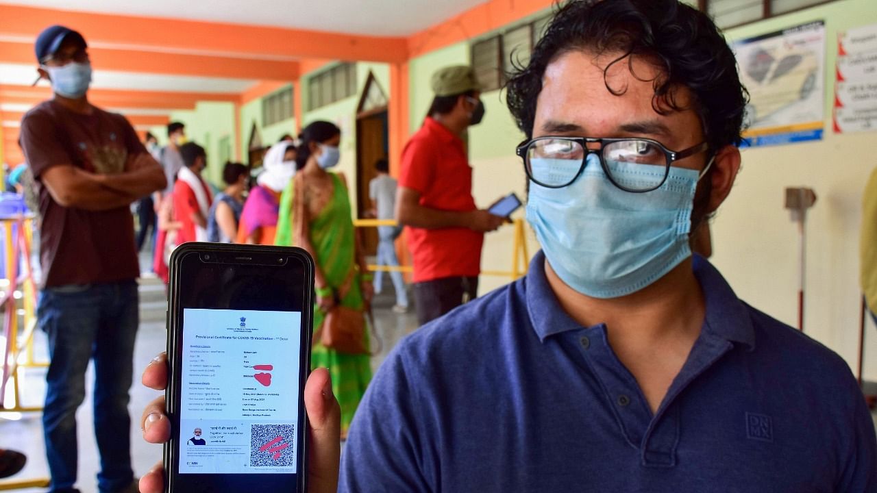 A man displays his vaccination certificate that bears the photo of PM Modi. Credit: PTI Photo