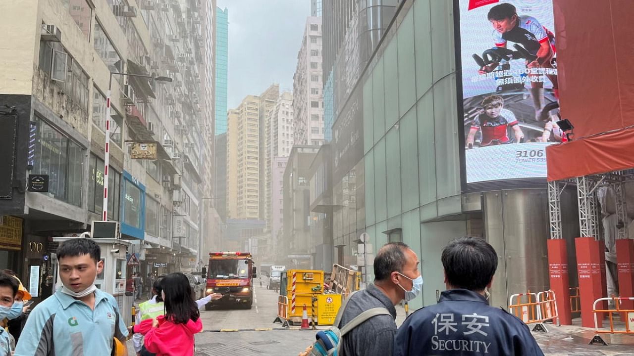 People walk as smoke coming from a fire that broke out at the World Trade Centre and a fire services vehicle are seen, in Hong Kong, China. Credit: Reuters Photo