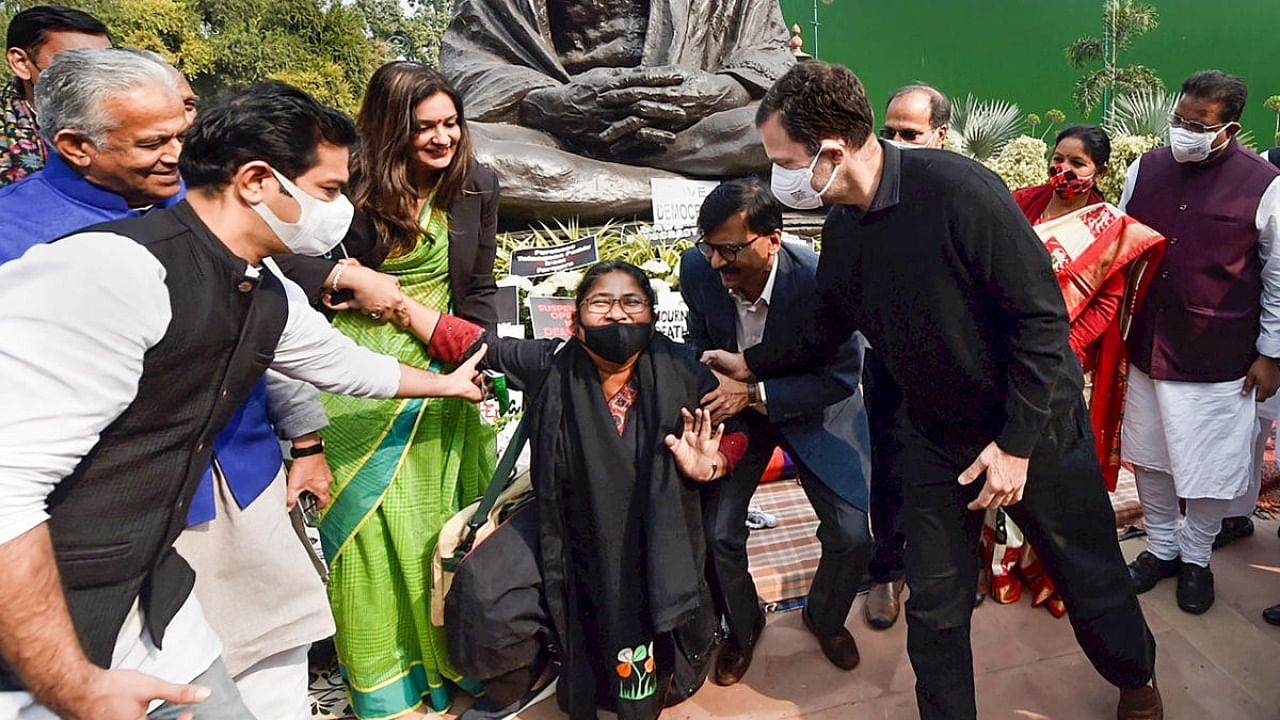 Congress MP Rahul Gandhi, Shiv Sena MPs Sanjay Raut and Priyanka Chaturvedi help suspended TMC MP Dola Sen to stand up, during the protest of Opposition parties' members demanding revocation of the suspension of 12 Rajya Sabha MPs, at Parliament premises. Credit: PTI photo